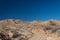 Wide path through the New Mexico desert leading up to a ridge before blue sky, road less traveled