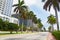 Wide road with tall palms and modern buildings in Miami Beach, Florida.