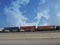 Wide roadside shot of a cargo train towing a string of container vans
