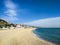 A wide sandy beach, the Mediterranean Sea with small waves and a bright blue sky