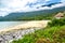 Wide sandy beach surrounded by stormy green vegetation