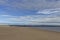 The wide sandy deserted beach of Tentsmuir Point on the southern edge of the Tay Estuary, with gentle waves breaking on the sand.