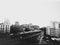 Wide scenic b&w photo of traffic flow on Brooklyn Queens Expressway in between buildings.