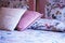 Wide selective shot of white and pink pillows on a bed with flower patterned sheets