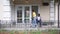 Wide shot African American man in wheelchair sitting on porch with soccer ball as teenage girl riding kick scooter in