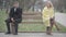 Wide shot of argued Caucasian couple sitting on opposite sides of bench in park and looking away. Irritated man and