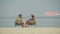 Wide shot of beautiful women sitting on sun loungers and applying sunscreen on legs. Slim gorgeous Caucasian tourists