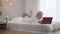 Wide shot bedroom with smiling carefree mature woman watching online comedy movie smiling lying on bed. Happy relaxed