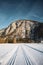 Wide shot of a big part of a mountain range surrounded by trees and a wide road covered in snow