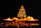 Wide shot of buddha statue with two glowing clay lamps and flowers on black background. buddhism concept