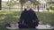 Wide shot of calm confident Caucasian woman sitting in lotus pose on exercise mat. Portrait of young female yogi