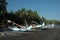 Wide shot of canoes on the shore by the sea surrounded by tropical trees under a clear sky