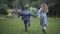 Wide shot of cheerful carefree children running to playground holding hands. Back view of happy Caucasian boy and girl