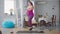 Wide shot of cheerful motivated overweight woman having fun working out with dumbbells at home. Side view of plus-size