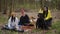 Wide shot cheerful young friends celebrating dog birthday on picnic in forest. Smiling Caucasian man and women putting