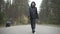 Wide shot of confident beautiful woman walking on empty road outdoors. Gorgeous young Caucasian biker in leather jacket