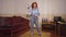 Wide shot confident retro woman posing with soccer ball indoors at home in 1980s 1990s. Wide shot positive redhead