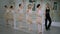 Wide shot focused young Caucasian ballerinas rehearsing tendu as choreographer walking talking in dance studio. Slim