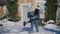 Wide shot of happy laughing Caucasian boyfriend holding girlfriend on back spinning in snow on backyard. Portrait of