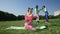 Wide shot happy woman peeling banana sitting on exercise mat with blurred women laughing pointing making fun of friend