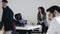 Wide shot, happy young boss business woman talking to two African male colleagues at busy modern office workplace table.