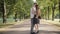 Wide shot of happy young couple strolling and start dancing in sunlight in summer park. Portrait of loving joyful