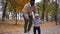 Wide shot happy young father playing with son in autumn park smiling. African American man spinning child putting kid on