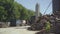 Wide shot of industrial manufacturing site with cement storage silo and felled tree logs lying outdoors in sunlight