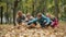 Wide shot of joyful carefree mothers and sons tossing yellow leaves in autumn park. Portrait of happy Caucasian families