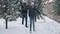 Wide shot of joyful daughter and father dancing in slow motion tossing snow outdoors. Happy cheerful smiling African