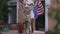 Wide shot joyful teenage boy dancing with American flag in slow motion standing on porch as happy military woman in