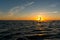 Wide shot of kitesurfer riding in sunset with silhouette