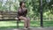 Wide shot of lonely upset senior woman sitting on bench in summer or spring park and thinking. Portrait of frustrated