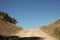 wide shot of long dirt dusty country road leading off into the distance on dry arid drought stricken agricultural farm land, rural