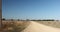 wide shot of long dirt dusty country road leading off into the distance on dry arid drought stricken agricultural farm land, rural