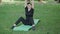 Wide shot of mid-adult Caucasian sportswoman sitting on sports mat and doing breathing exercises. Portrait of active