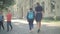 Wide shot of mother and daughter walking along sunny schoolyard and talking. Back view of positive schoolgirl with