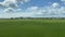 Wide shot out of a window of train, tracking along flat british UK southern England countryside and farmland clouds and blue sky -