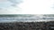 Wide shot of picturesque seascape with foamy calm Mediterranean sea waves rolling on pebbles on coastline. Beautiful