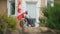 Wide shot portrait of adult African American man in wheelchair thinking sitting on porch with Canadian flag fluttering