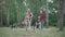 Wide shot portrait of Caucasian couple walking with dogs for picnic in summer forest or park. Smiling man and woman with