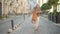 Wide shot portrait of cheerful senior man and cute little girl jumping and dancing on city street. Happy carefree