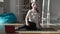 Wide shot portrait of confident pregnant young woman sitting on exercise mat watching online fitness lesson on laptop