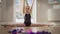 Wide shot portrait of confident pretty teen gymnast looking at camera sitting on twine raising arms up. Front view of