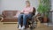 Wide shot portrait of depressed frustrated disabled woman sitting in wheelchair at home thinking. Young paralyzed