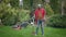 Wide shot portrait of happy young man standing with shovel outdoors looking away thinking. Cheerful African American