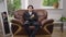 Wide shot portrait of serious thoughtful young Asian man in wedding suit with boutonniere sitting on comfortable