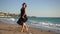 Wide shot portrait of talented happy beautiful female dancer walking on scenic sandy sea beach. Confident gifted