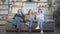 Wide shot portrait of three confident young Caucasian women sitting on couch crossing legs. Beautiful female friends