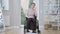 Wide shot portrait of young Caucasian handicapped woman sitting on wheelchair thinking. Sad disabled invalid at home